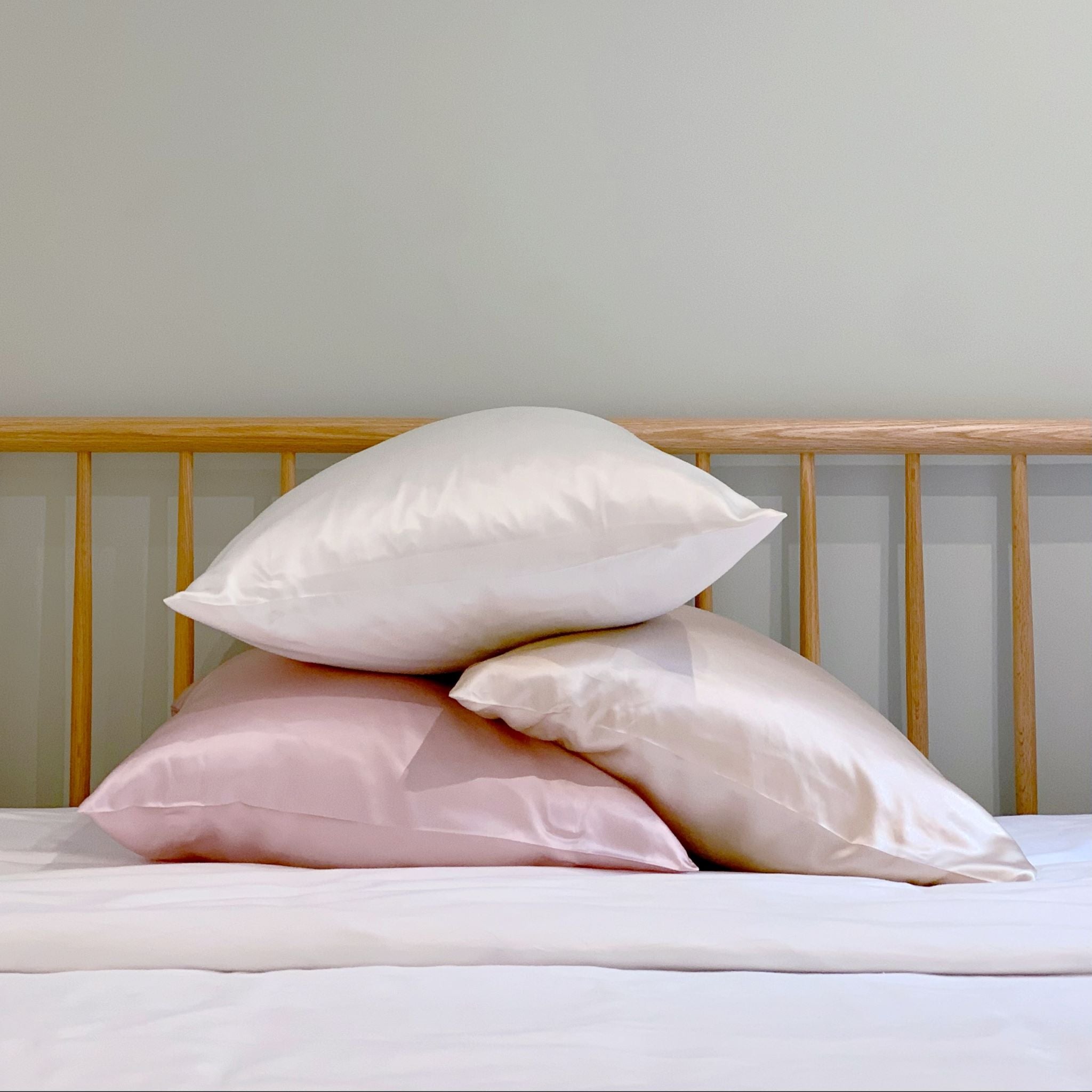 Three Silk Pillowcases in Ivory Blush Champagne Stacked on Bed